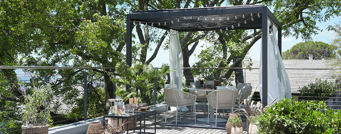 Pergola metallica con tetto, decorata con tende in voile e catena di luci su patio